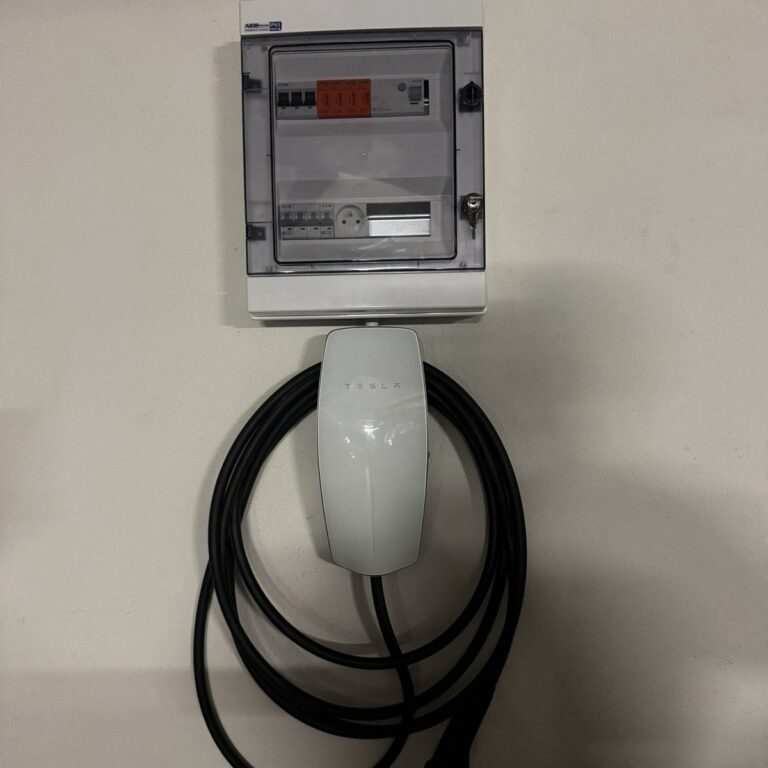 Wallbox Tesla Wall Connector z dedykowaną rozdzielnicą na ścianie garażu podziemnego bloku w Krakowie
