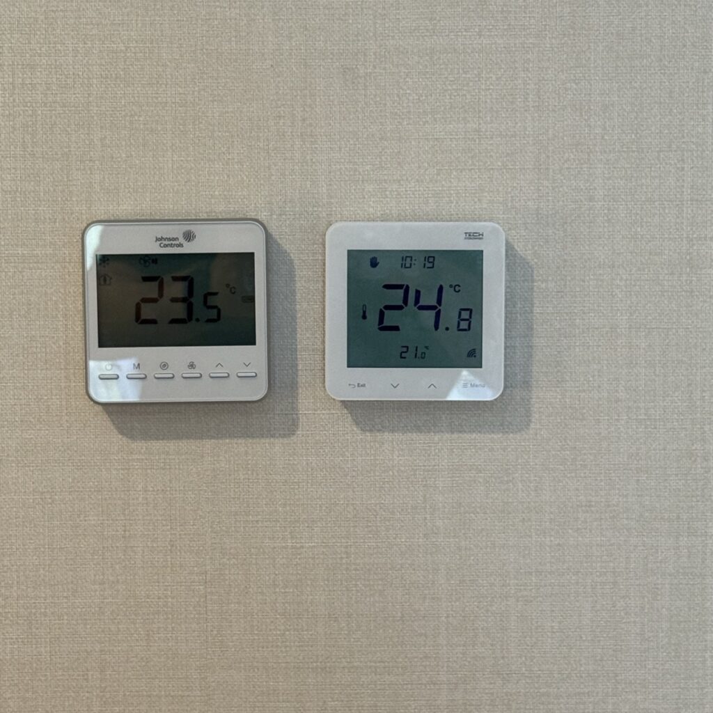 Regulator temperatury Sinum obok sterownika klimakonwektora w pokoju hotelowym w Mielnie